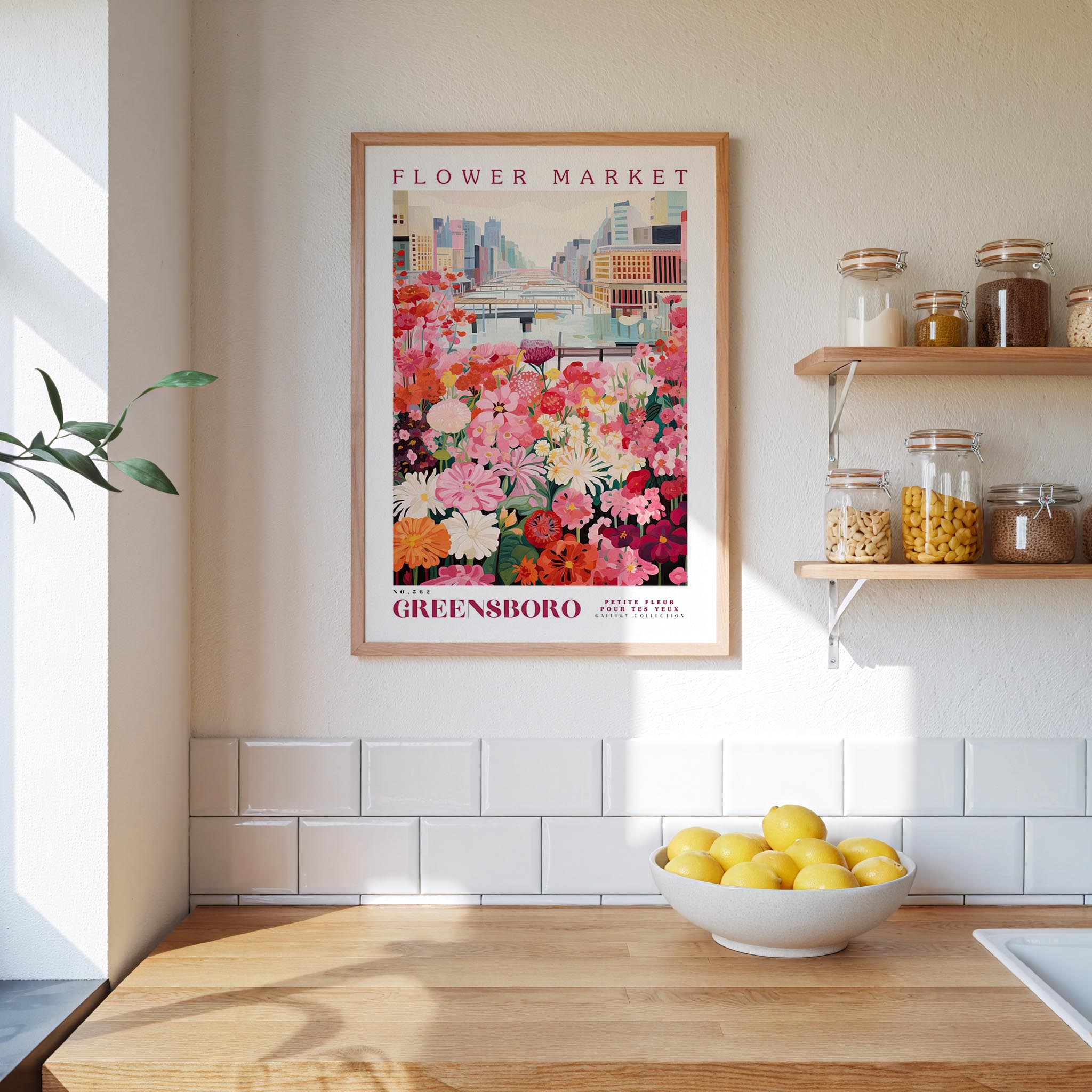 a framed poster of a colorful flower market in Greensboro, North Carolina, hanging on a wall above a kitchen counter with a bowl of lemons.