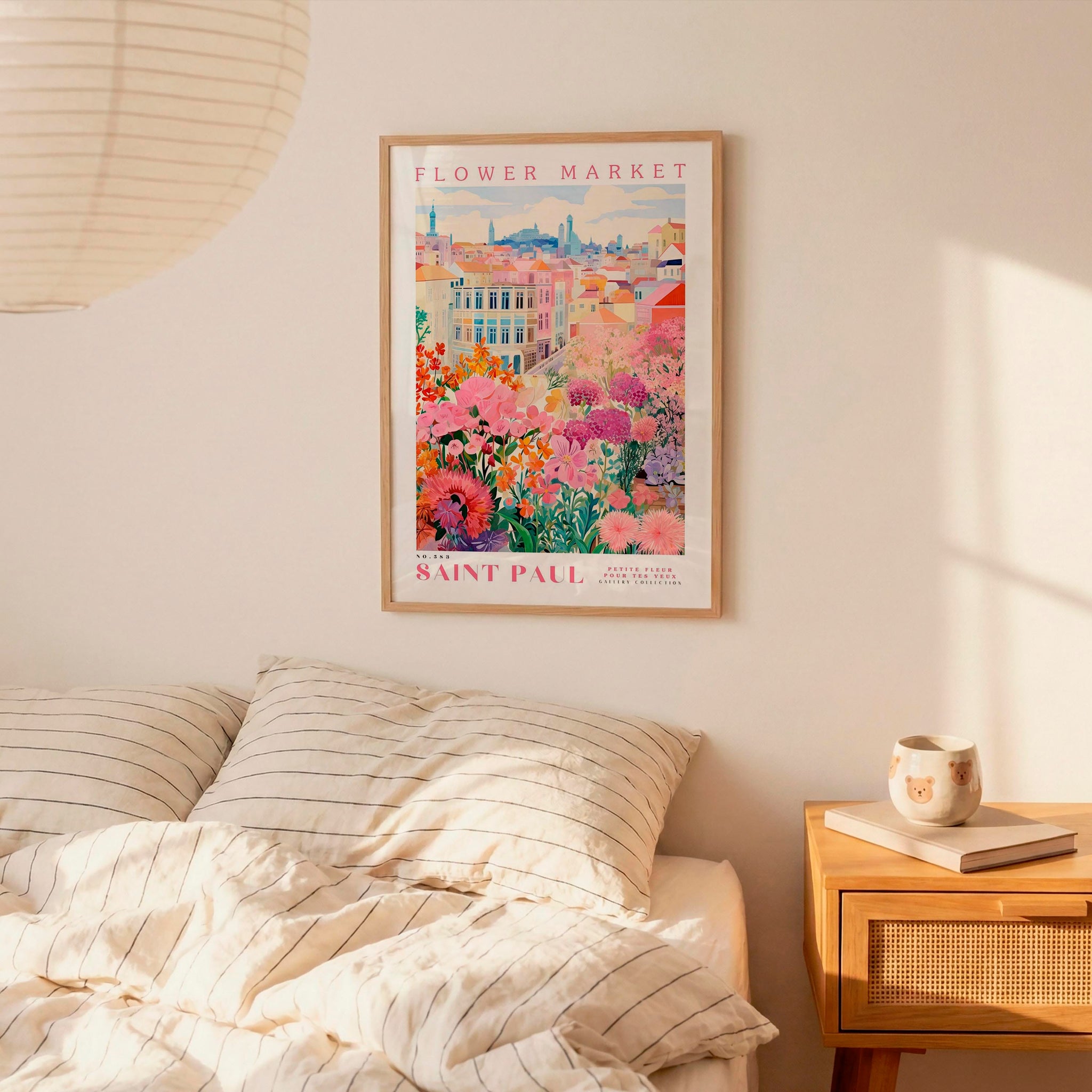 a bedroom setting with a framed poster of a colorful floral scene hanging on the wall above a bed with striped pillows.