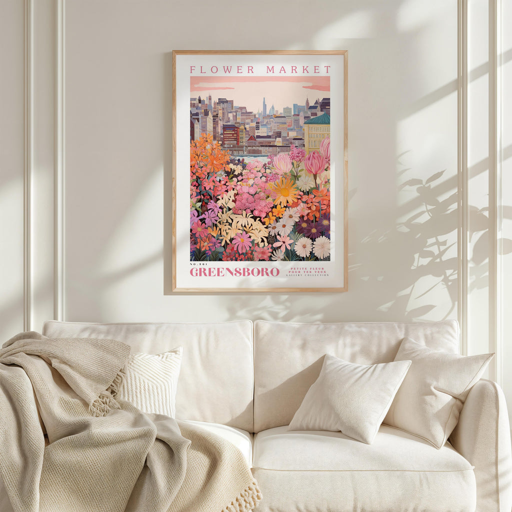 a framed poster of a colorful garden scene with flowers, hanging on a wall above a white couch.