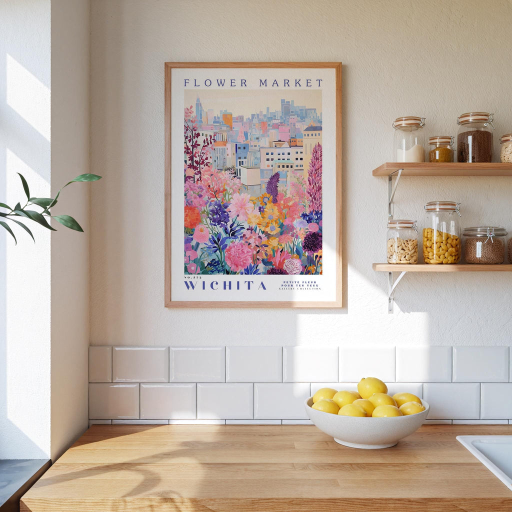 a kitchen counter with a bowl of lemons, a framed poster of a flower market in Wichita, and a shelf with jars and other kitchen items.