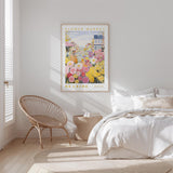 a serene bedroom scene with a bed, a woven chair, and a framed poster of a flower market.
