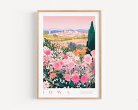 A framed poster depicting a vibrant garden filled with pink and white flowers, with a cityscape visible in the background.