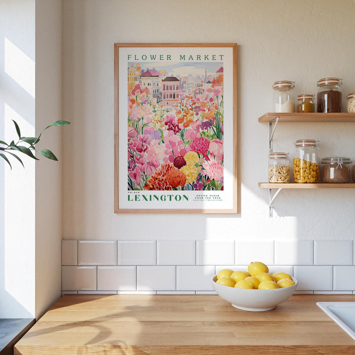 a framed poster of a flower market in Lexington, Kentucky, hanging on a wall above a kitchen counter with a bowl of lemons on it.