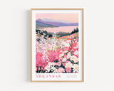 A framed poster depicting a scenic landscape with mountains, a lake, and a field of colorful flowers, including pink, white, and purple blooms.