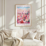 a framed poster of a colorful floral scene hanging on a wall above a white couch with a blanket draped over it.