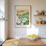 a framed poster of a field of flowers hanging on a wall above a wooden countertop with a bowl of lemons.