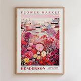 A framed poster depicting a vibrant and colorful flower market, with a variety of flowers and buildings in the background.