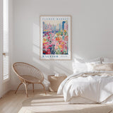 a bedroom with a bed, a wicker chair, and a framed poster of a flower market in Raleigh, North Carolina.