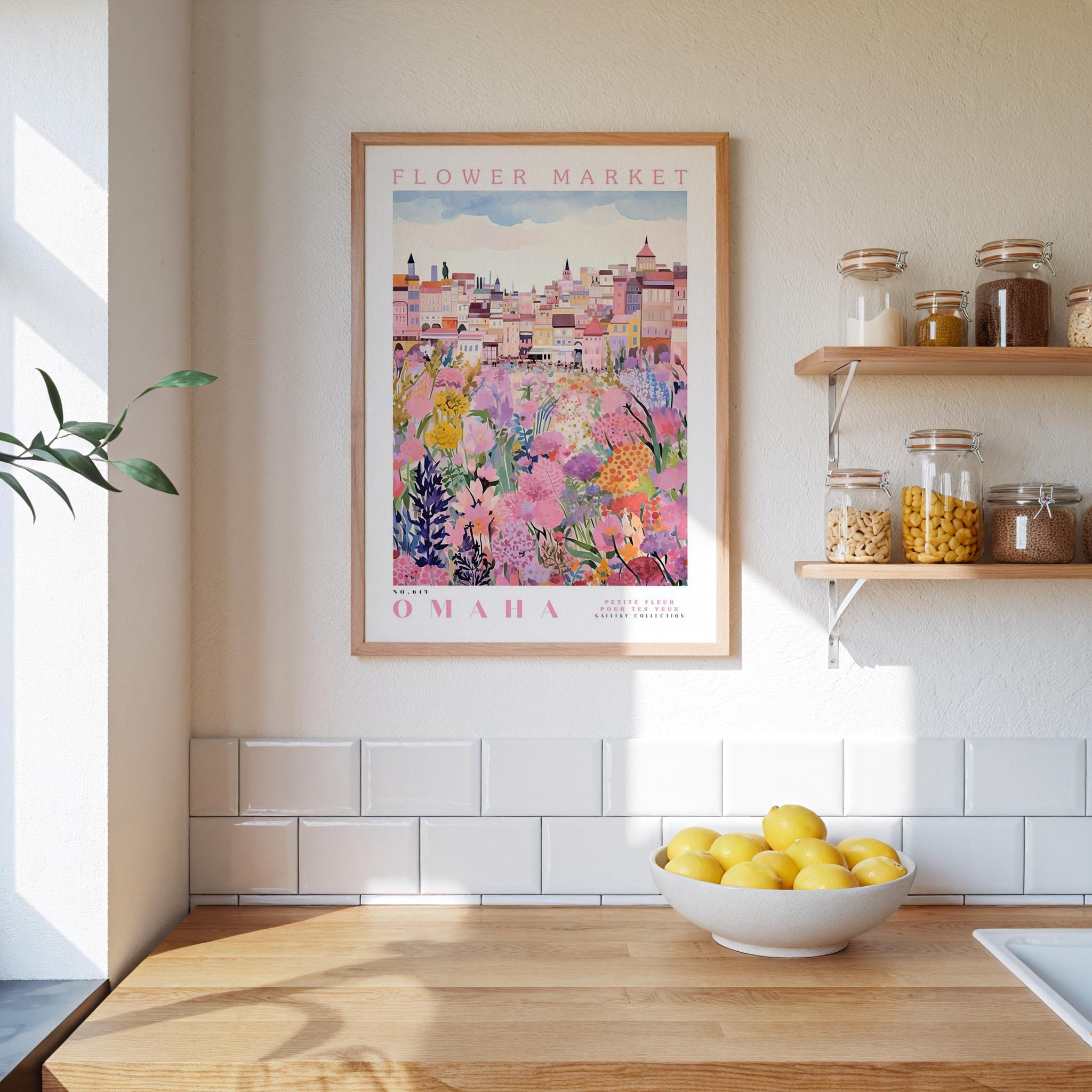 a kitchen scene with a framed poster of a colorful flower market in Omaha, Nebraska, hanging on the wall above a wooden counter. The poster is surrounded by various kitchen items, such as jars, a bowl of lemons, and a plant.