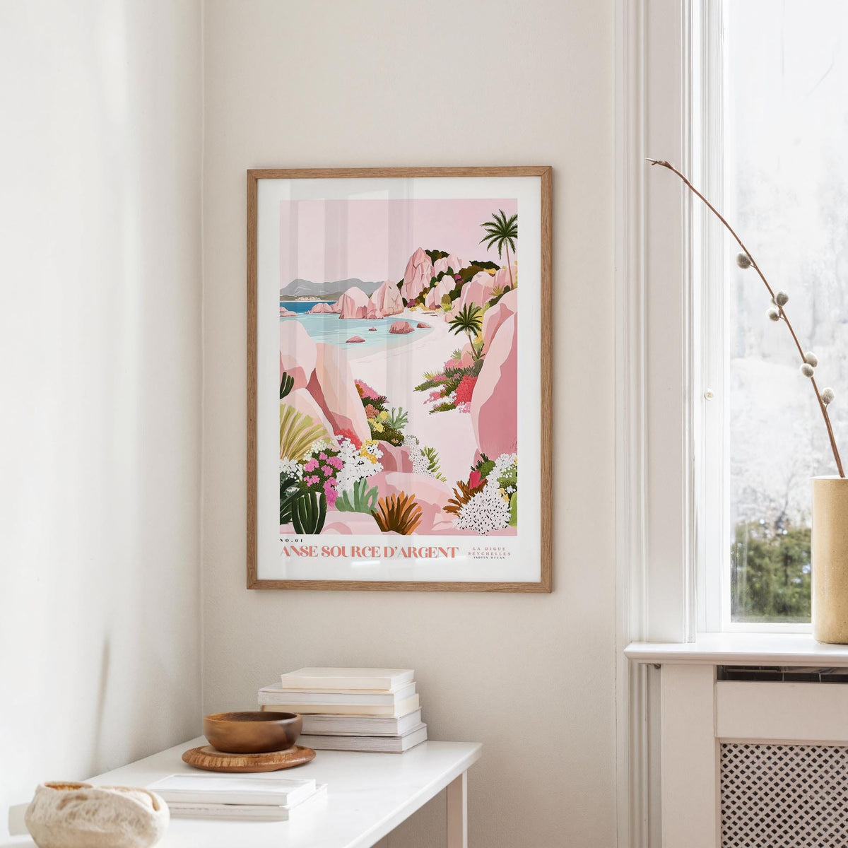 a framed poster of a tropical landscape hanging on a wall, with a white table and a plant in the foreground.
