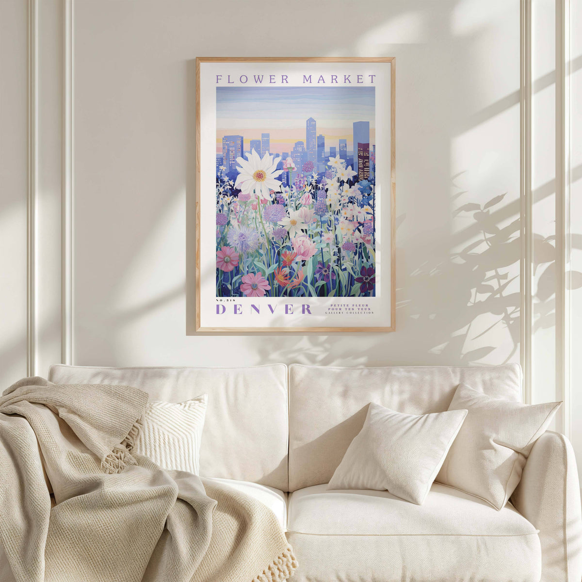 a framed poster of a cityscape with flowers hanging on a wall above a white couch with pillows.