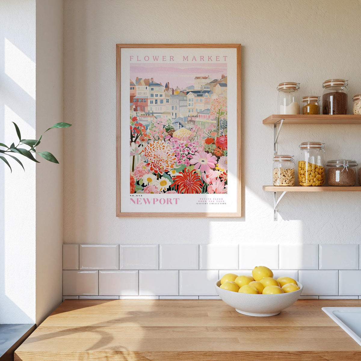 a kitchen scene with a framed poster of a flower market in Newport, Rhode Island, hanging on the wall above a wooden counter. The poster displays a colorful illustration of the flower market, and there is a bowl of lemons on the counter.