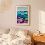 a bedroom scene with a framed poster of a colorful underwater landscape hanging on the wall above a bed with striped pillows.