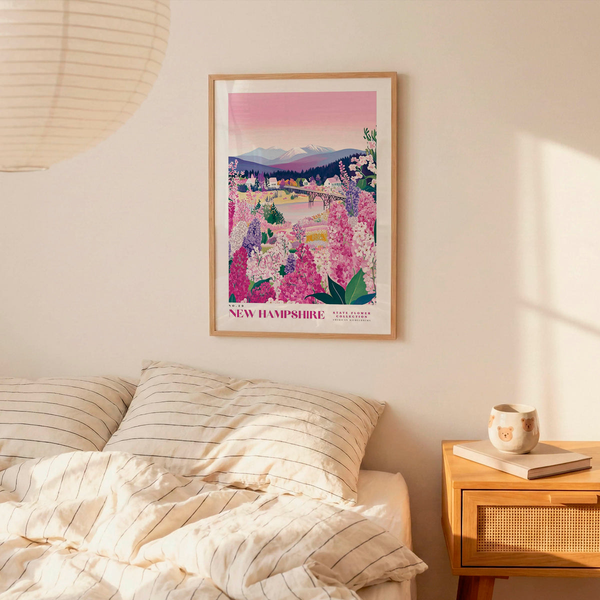 a bedroom scene with a framed poster of a scenic landscape hanging on the wall above a bed with striped pillows.