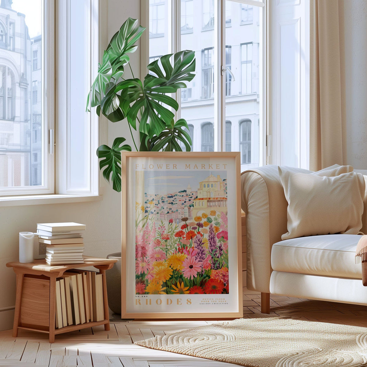 a living room with a large framed poster of a colorful floral scene hanging on the wall, a stack of books on a wooden shelf, a white sofa, and a large window with a view of buildings outside.