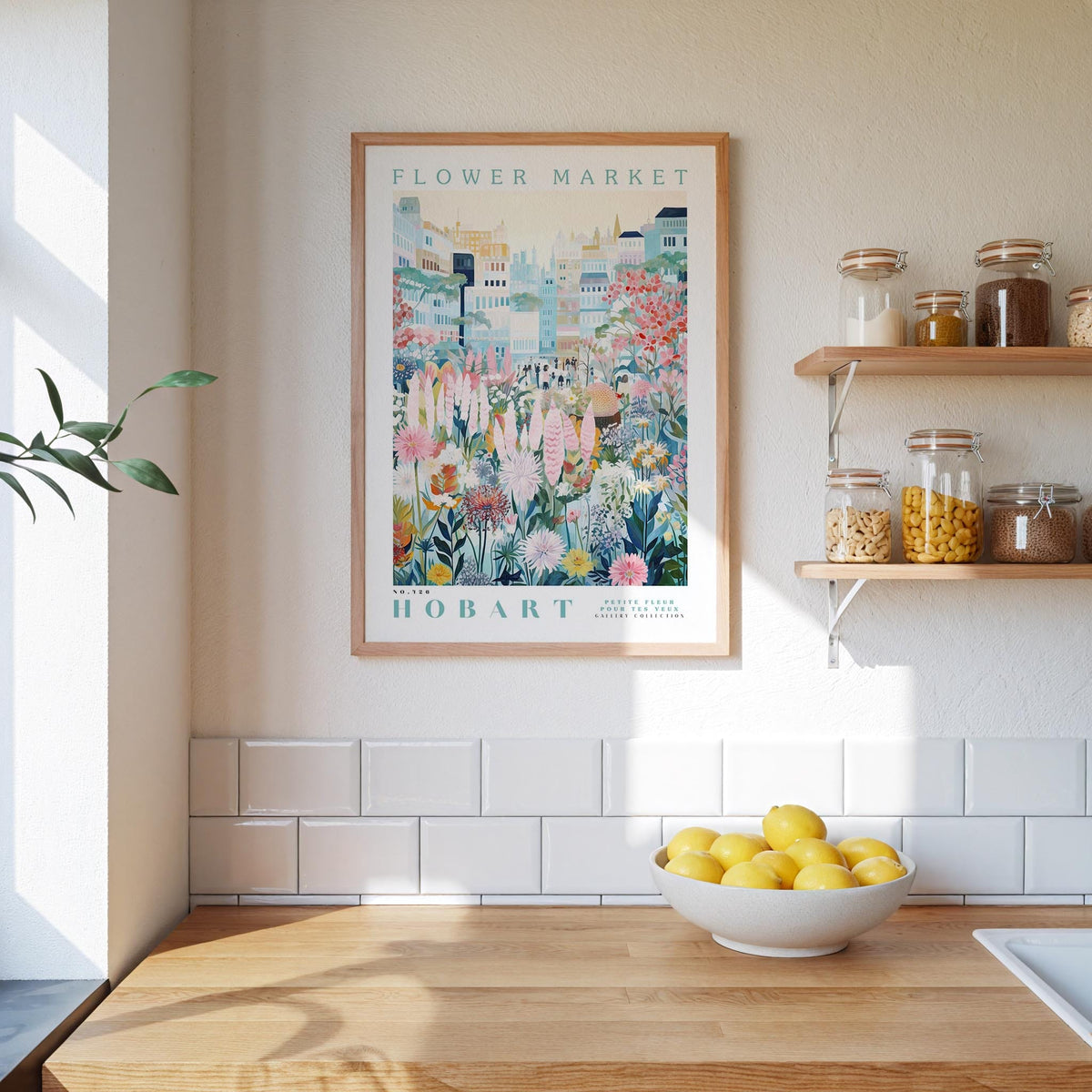 a kitchen scene with a framed poster of a flower market in Hobart hanging on the wall above a wooden counter with a bowl of lemons.
