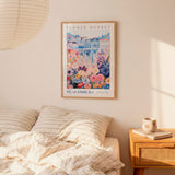 a bedroom scene with a framed poster of a colorful floral scene hanging on the wall above a bed with striped pillows.
