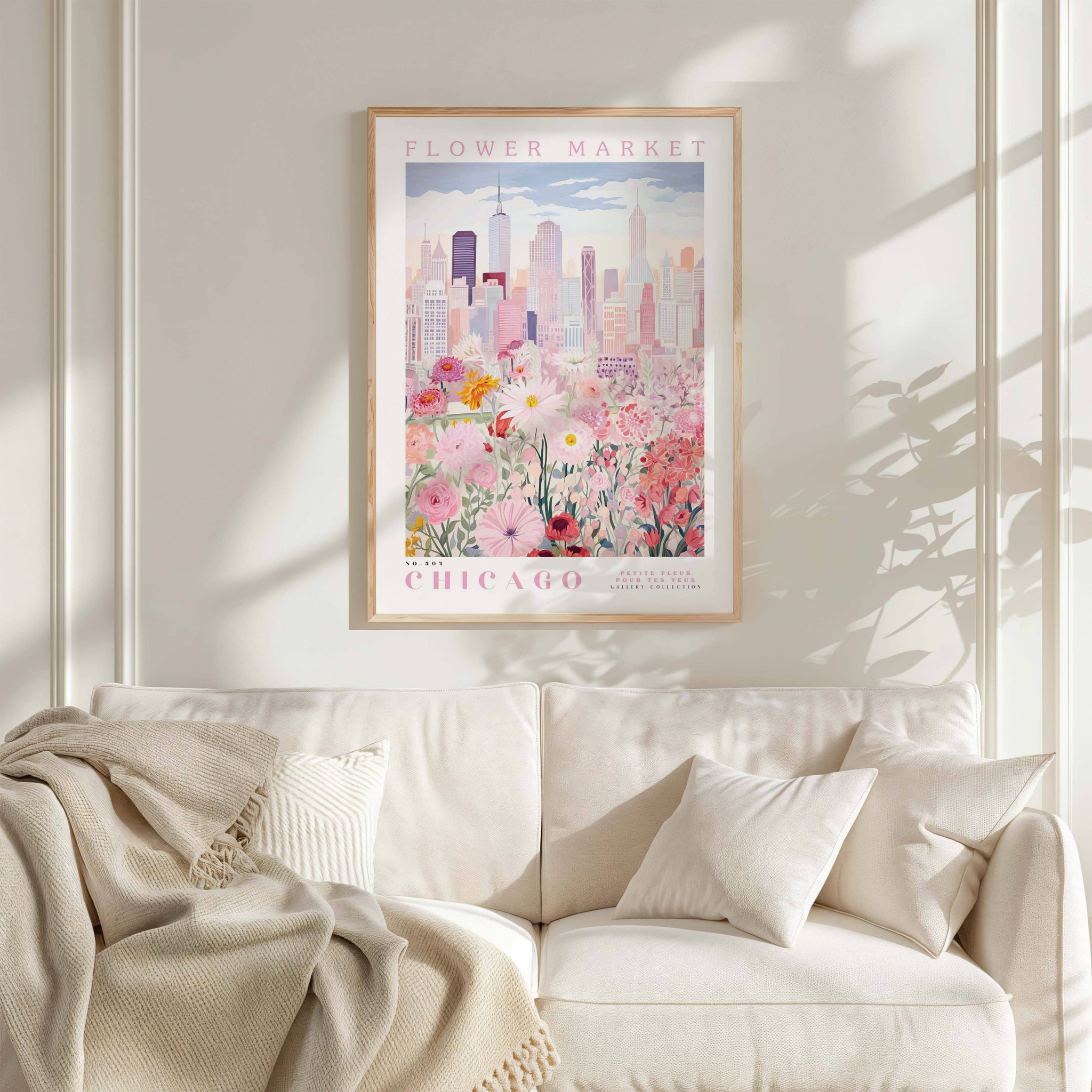 a framed poster of a cityscape with a flower market in the background, hanging on a wall above a white couch with pillows.