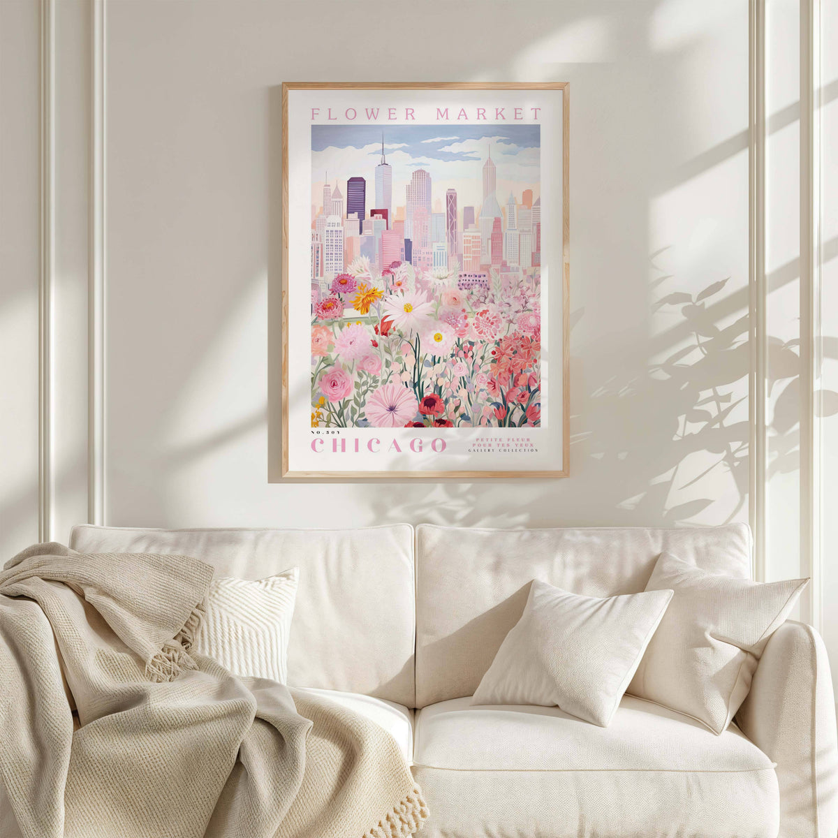 a framed poster of a cityscape with a flower market in the background, hanging on a wall above a white couch with pillows.