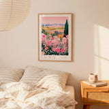 a bedroom scene with a framed poster of a field of flowers hanging on the wall above a bed with striped pillows.