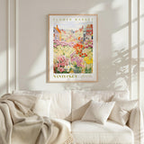 a framed poster of a colorful garden scene hanging on a wall above a white couch.
