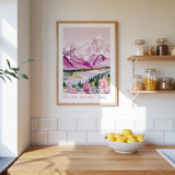 a kitchen counter with a bowl of lemons, a framed poster of a mountain landscape, and a shelf with jars and bottles.