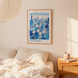 a bedroom scene with a framed poster of a cityscape hanging on the wall above a bed with striped pillows.