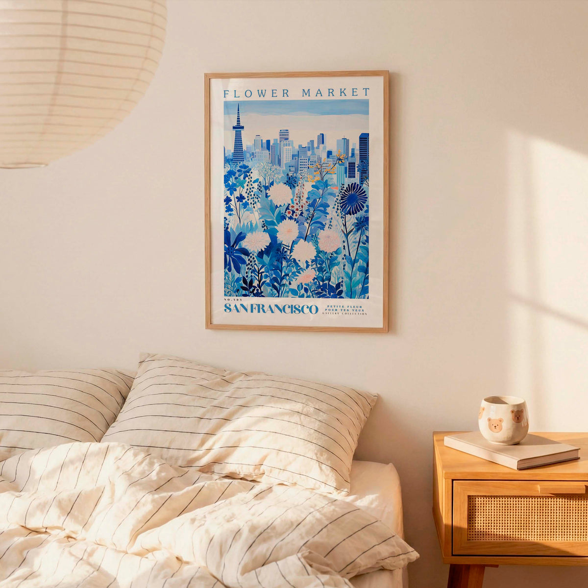a bedroom scene with a framed poster of a cityscape hanging on the wall above a bed with striped pillows.