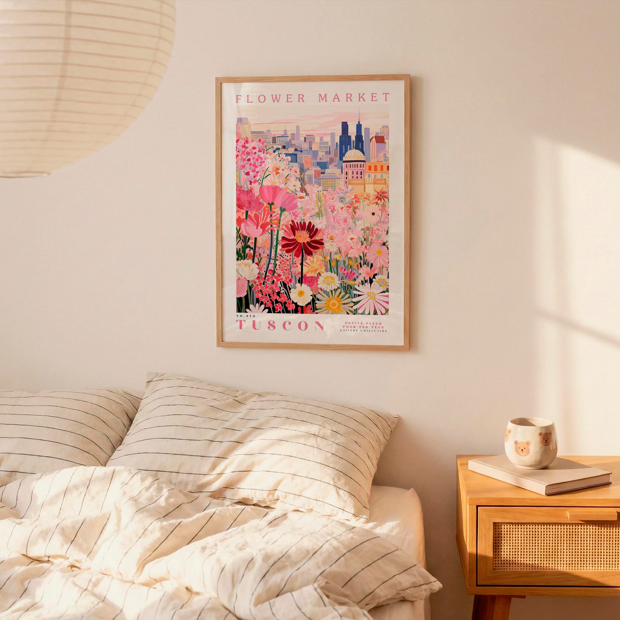 a bedroom scene with a framed poster of a colorful floral scene hanging on the wall above a bed with striped pillows.