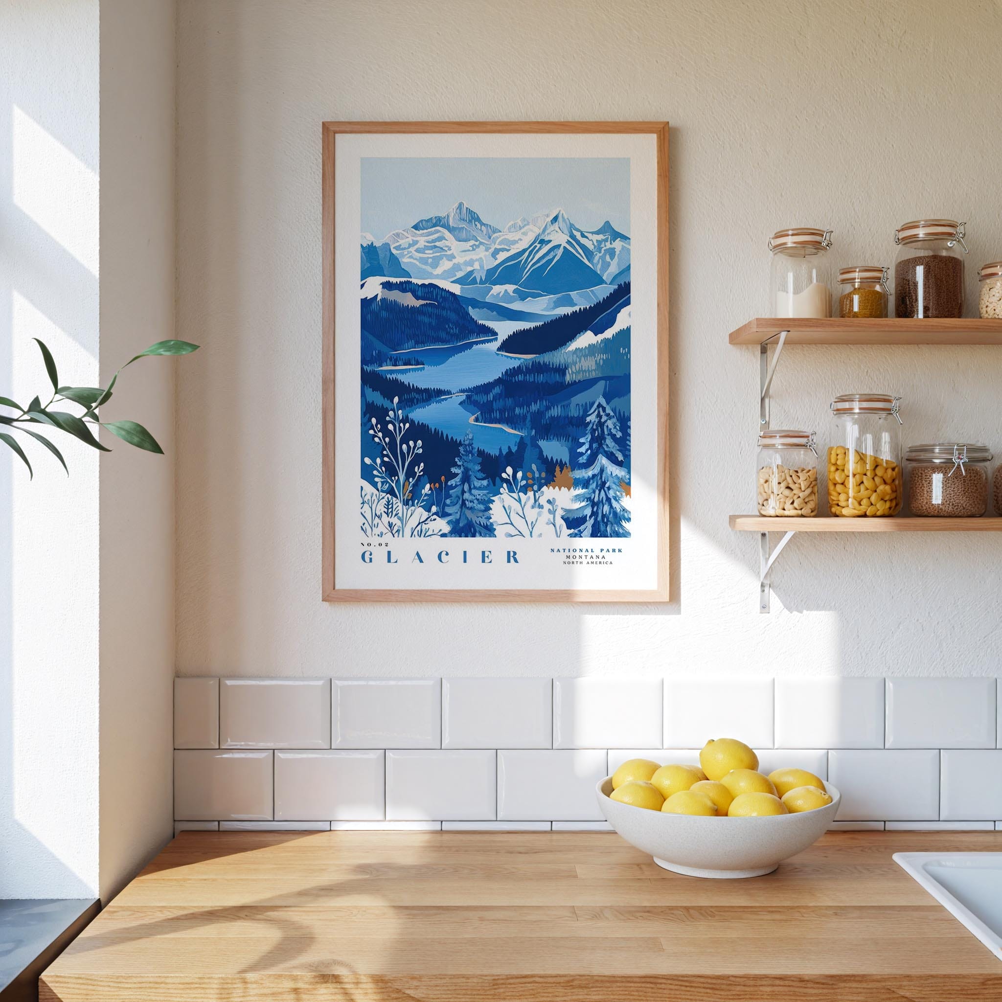 a framed poster of a mountainous landscape with a blue and white color scheme, hanging on a wall above a wooden countertop with a bowl of lemons.