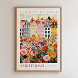 The image is a framed poster depicting a colorful and vibrant flower market in Amsterdam, with a variety of flowers and buildings in the background.