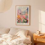 a framed poster of a colorful floral scene hanging on a wall above a bed with striped pillows.