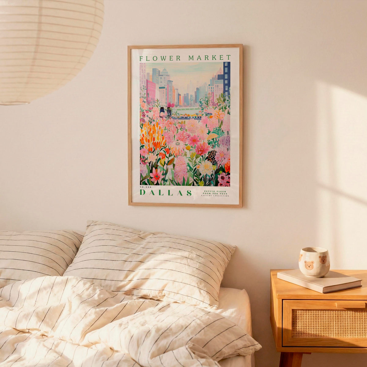 a framed poster of a colorful floral scene hanging on a wall above a bed with striped pillows.