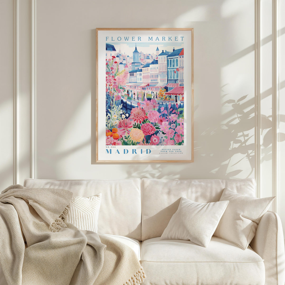 a poster of the "Flower Market" in Madrid, Spain, hanging on a wall above a white couch.
