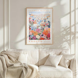 a cozy living room with a white sofa and a framed poster of a colorful floral scene hanging on the wall above it.