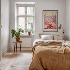 a cozy bedroom with a large bed, a nightstand with a potted plant, and a framed poster of a cityscape on the wall.