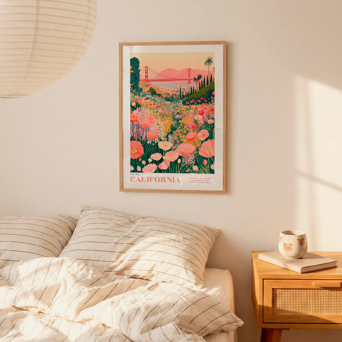 a framed poster of a colorful floral landscape hanging on a wall above a bed with striped pillows.