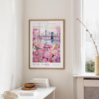 a framed poster of a flower market in New York, with a bridge and colorful flowers in the background.