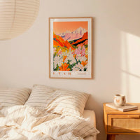 a bedroom with a framed poster of a mountain landscape hanging on the wall above a bed with striped pillows.
