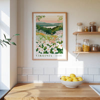 a framed poster of a garden with white flowers hanging on a wall above a wooden table with a bowl of lemons.