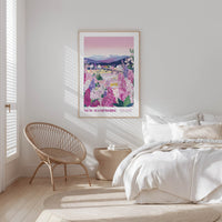 a bedroom with a large framed poster of a scenic landscape hanging on the wall, a woven chair, and a bed with white bedding.