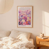 a bedroom scene with a framed poster of a colorful cityscape hanging on the wall above a bed with striped pillows.