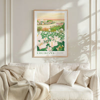 a framed poster of a field of flowers hanging on a wall above a white couch with pillows.