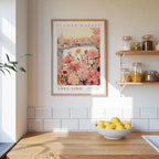 a framed poster of a flower market in Adelaide, Australia, hanging on a wall above a wooden counter with a bowl of lemons.