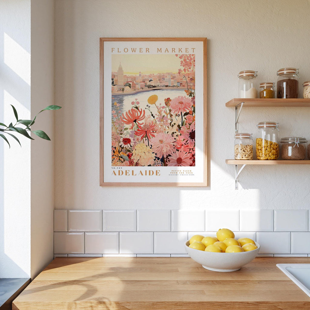 a framed poster of a flower market in Adelaide, Australia, hanging on a wall above a wooden counter with a bowl of lemons.