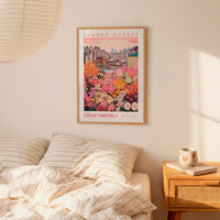 a bedroom scene with a framed poster of a cityscape and a bed with striped pillows.
