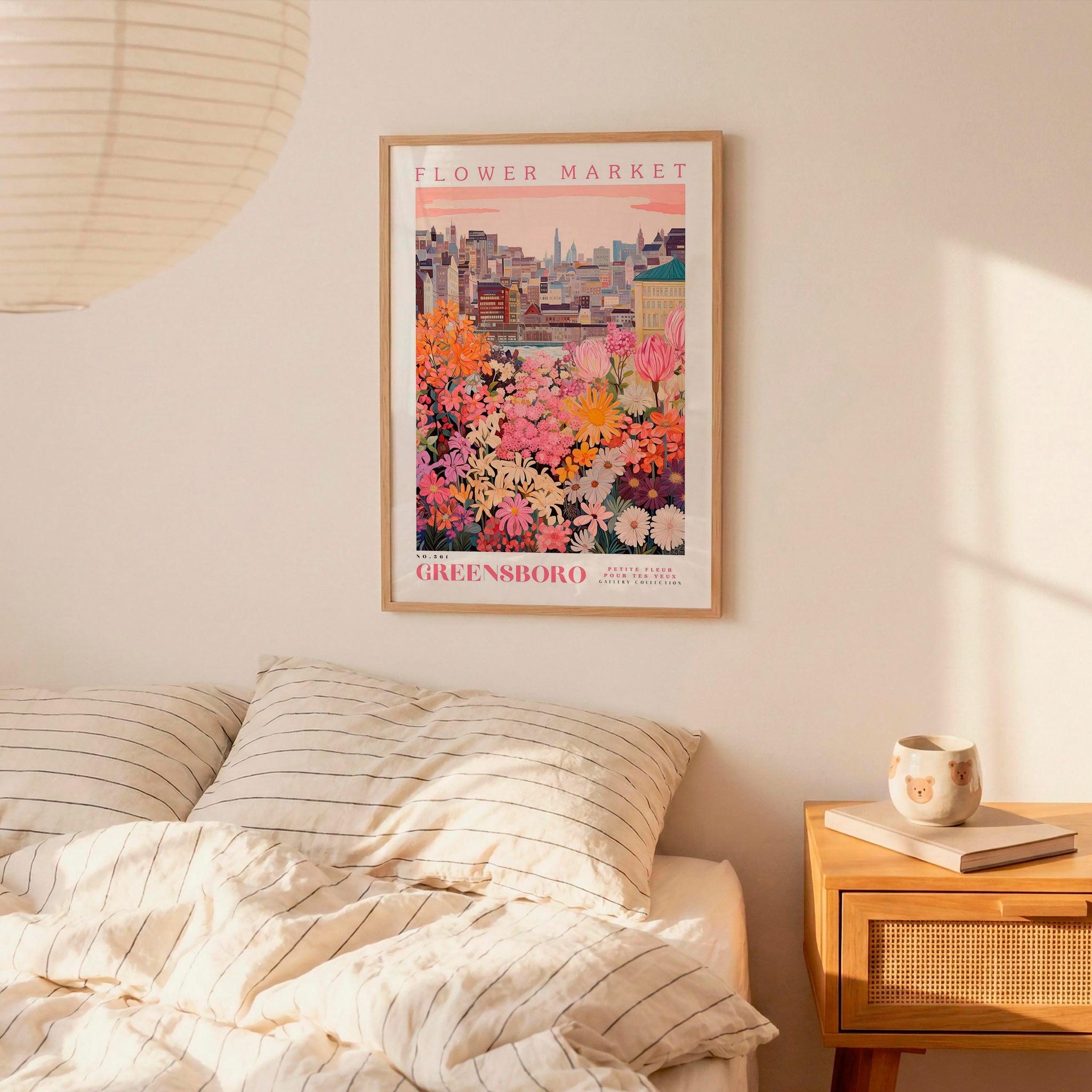 a bedroom scene with a framed poster of a cityscape and a bed with striped pillows.