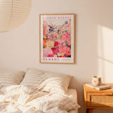 a bedroom setting with a framed poster of a flower market hanging on the wall above a bed with striped pillows.