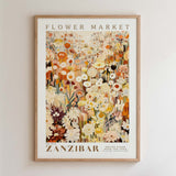 The image is a framed poster depicting a vibrant and colorful flower market in Zanzibar, featuring a variety of flowers and plants in different shades of orange, yellow, and white.