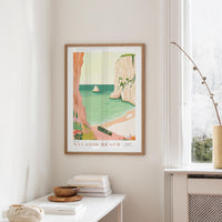 a framed poster of a beach scene with a boat, palm trees, and a rocky cliff, hanging on a wall in a room with a window and a small table with books and a bowl.